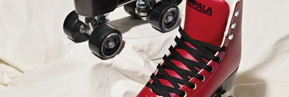 A pair of cherry red Impala roller skates beside a bowl of cherries