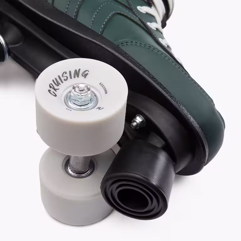 A close up of a white wheel on a green roller skate with the word "Cruising" visible on the wheel